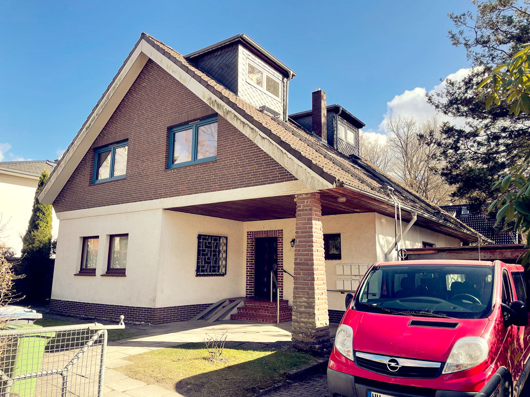 Ein Haus mit Carport und einem geparkten Auto davor.
